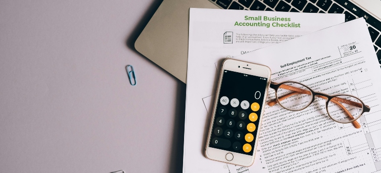 Calculator and checklist on a desk, symbolizing careful financial planning for moving expenses.