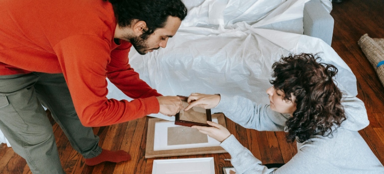 Two individuals carefully packing and framing delicate items to ensure their safety during a move.