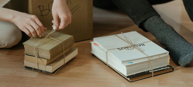 Books tied in bundles on the floor, being prepared for packing.