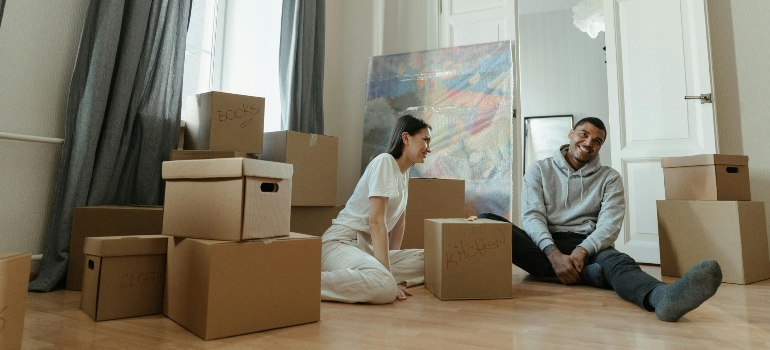 A couple sitting among labeled boxes, preparing for a hassle-free move with movers Cumming GA.