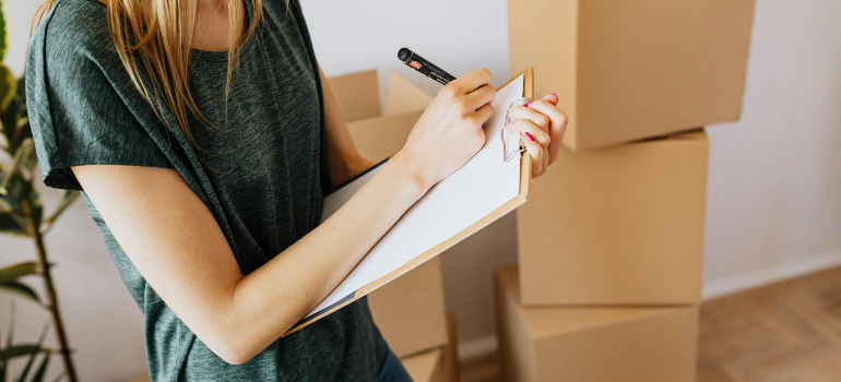 woman writing a moving checklist including tips for moving across the country