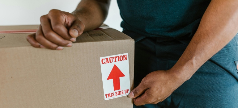 Close-up of a caution sticker on a moving box, handled by a mover.