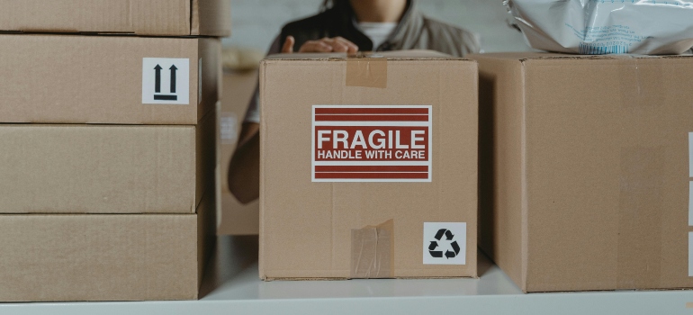 Close-up of a cardboard box labeled "Fragile - Handle with Care" among other moving boxes, highlighting secure packing for office and commercial movers.