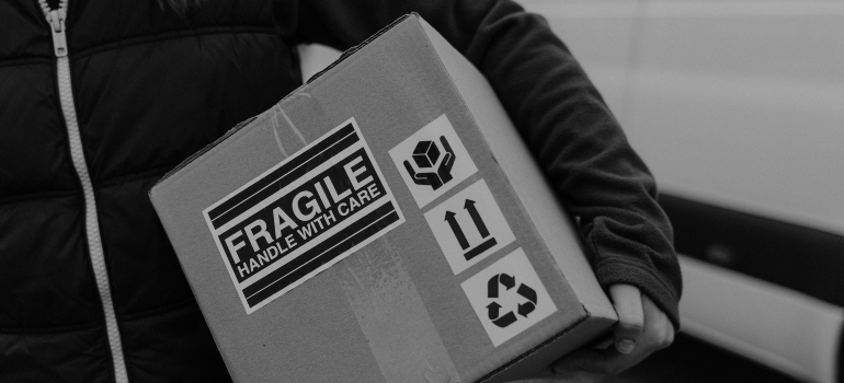 person carrying a box with a fragile label on it