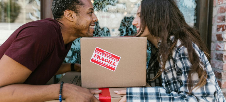 a couple holding a packed box