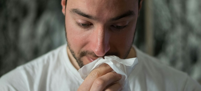 Person cleaning their nose with tissue paper while thinking about the pros and cons of living in Atlanta 