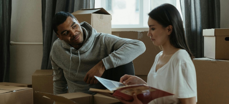 Two friends pausing to appreciate a special keepsake while organizing their belongings.