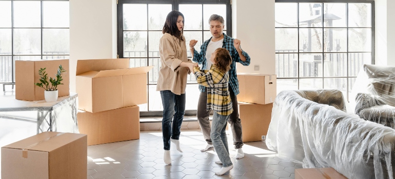 A happy family dancing in their freshly unpacked living room, boxes stacked neatly after a successful move by movers Decatur GA.