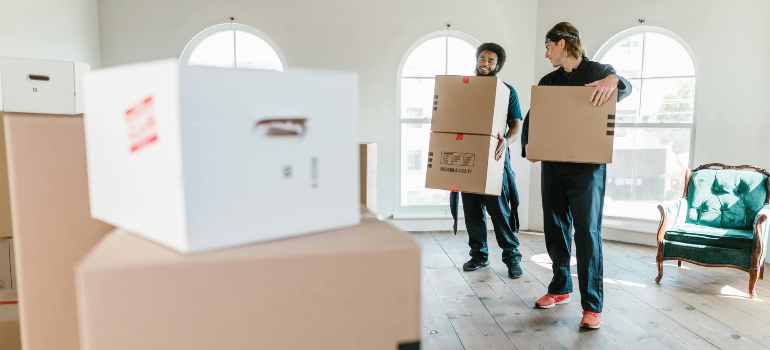 Two professional movers working efficiently in a bright, spacious room.