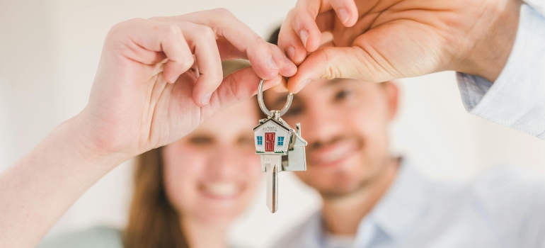 Close-up of a couple holding house keys, symbolizing their new beginning in a new home after moving to Atlanta