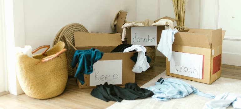 Several boxes labeled keep, donate, and trash line a floor, helping sort belongings before relocation.