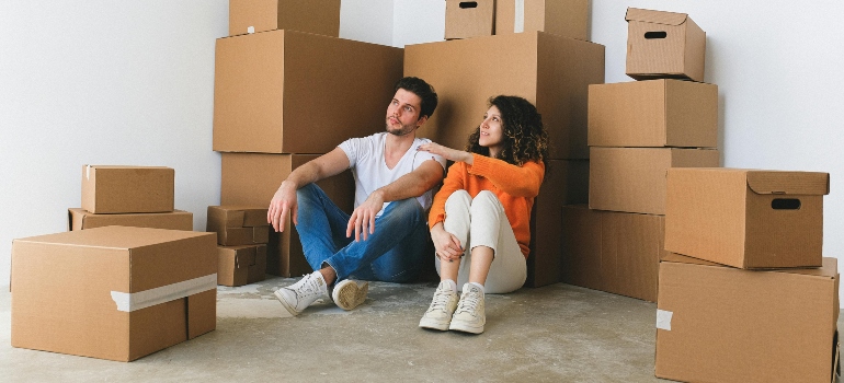 A couple sitting on the floor surrounded by moving boxes, reflecting on their new chapter.