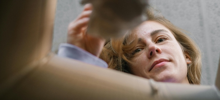 Close-up of a woman looking into a box, emphasizing efficient packing tips for moving out for the first time.