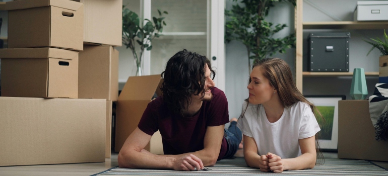 A relaxed couple lying next to neatly stacked boxes, sharing a quiet, comforting moment after moving day organized by Decatur movers.