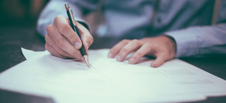 Person signing documents after researching the pros and cons of living in Atlanta 