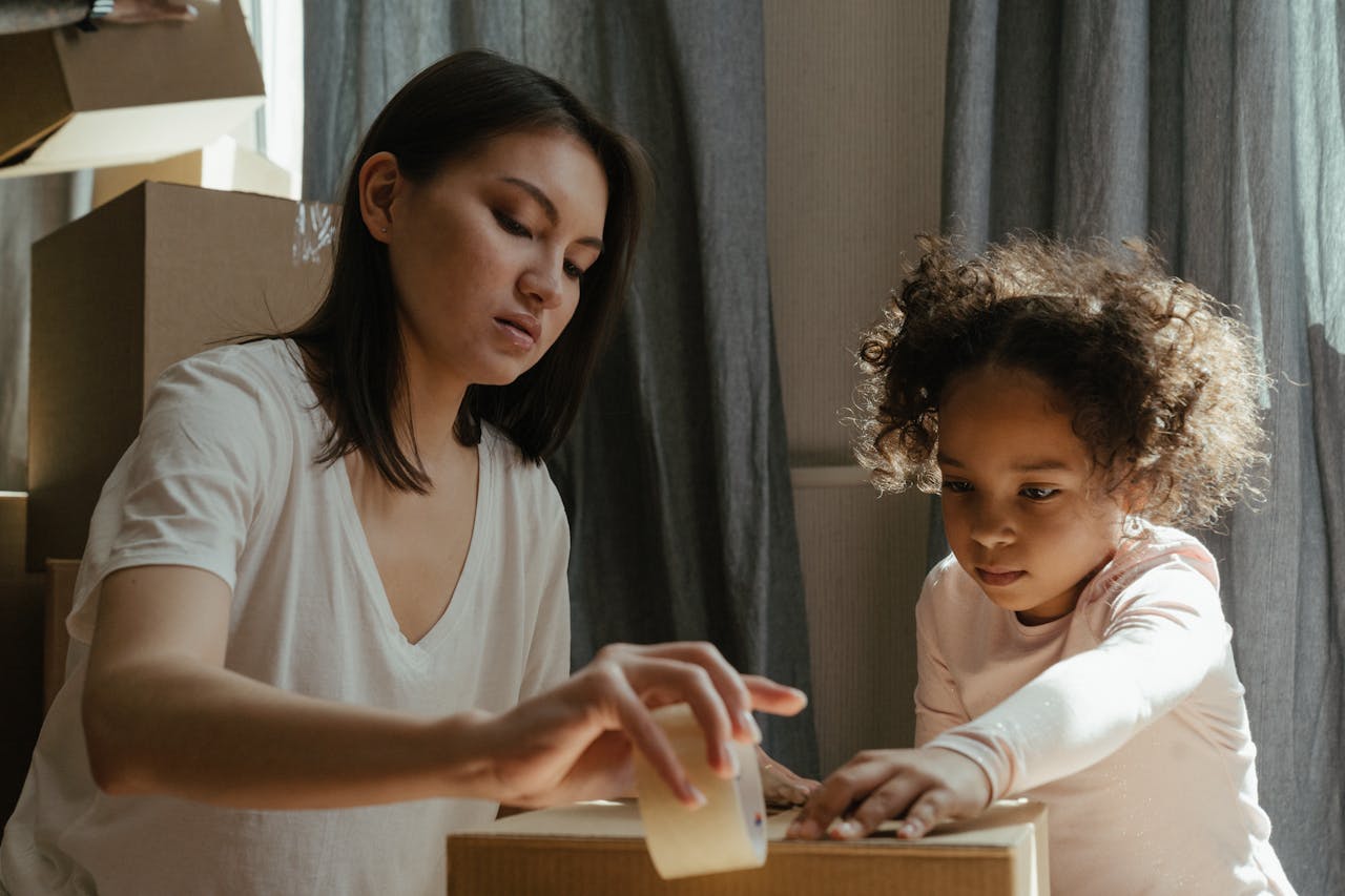 a woman packing boxes with her child