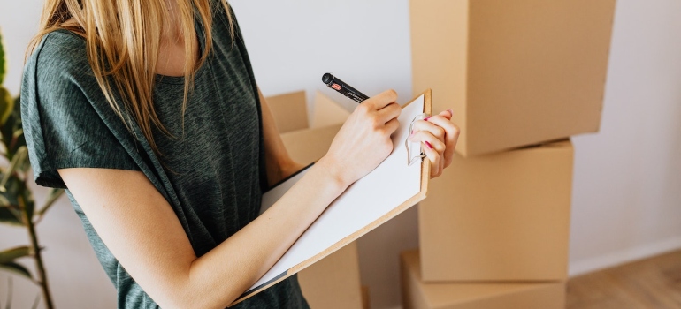 a woman surrounded by boxes making a packing checklist