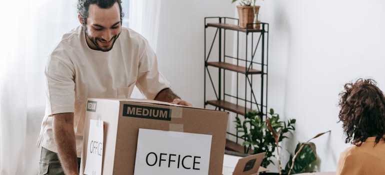 a man carrying a box labelled 'office'