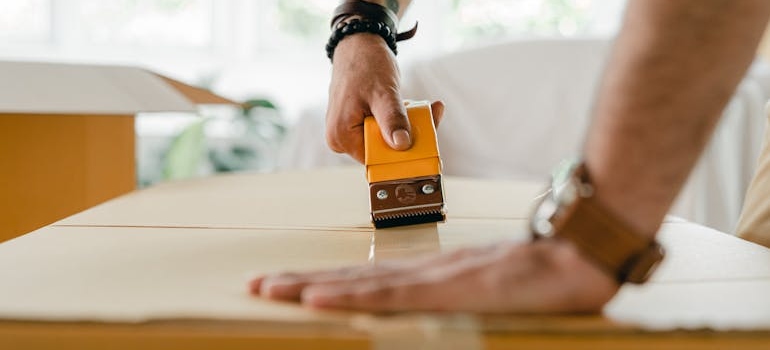 a man sealing a box with a tape