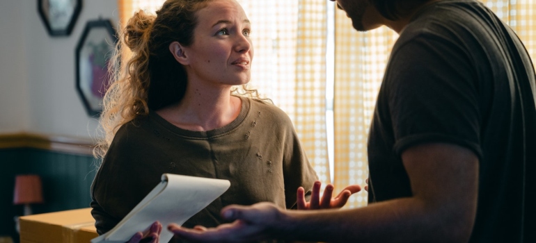 a woman holding an inventory list and explaining something to a man