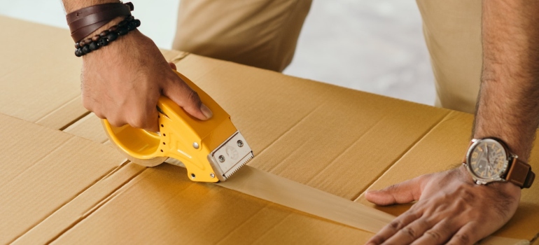a person sealing the box after attic decluttering