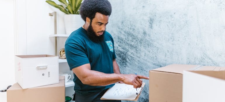 a mover checking a room-by-room packing plan and the boxes
