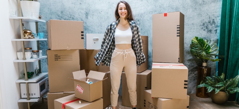 a happy woman standing next to carboard boxes