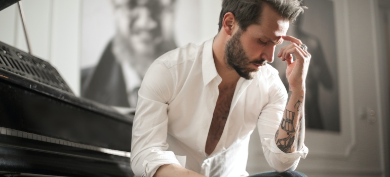 a man sitting next to a piano thinking about how to pack fragile items.