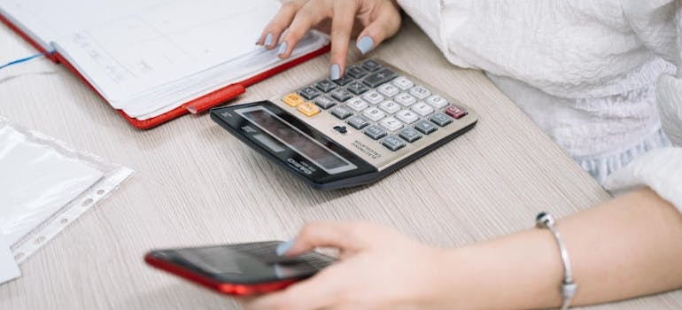 a woman calculating on  both phone and calculator