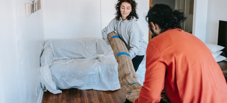 two people moving rugs and carpets