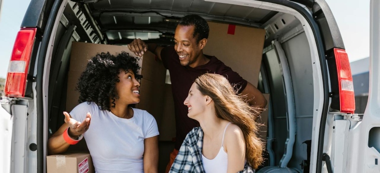 three people sitting in a back of a moving van about to organize a residential move based on a home type