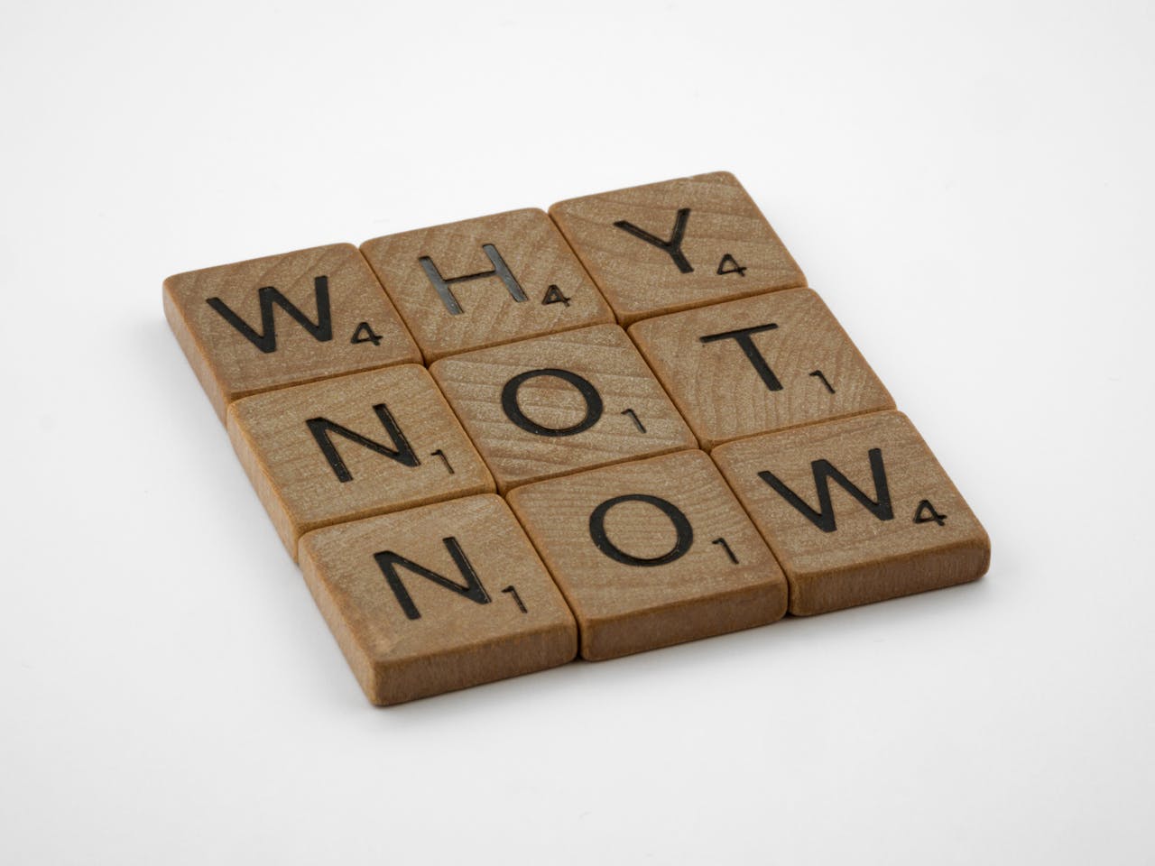 wooden scrabble letters forming the phrase 'why not now'