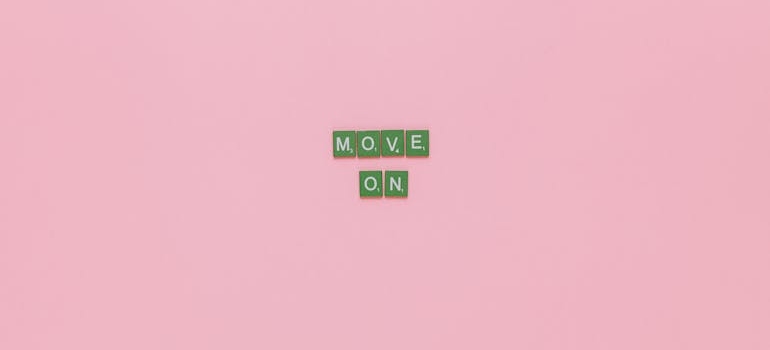 green scrabble letters on a pink background forming the phrase 'move on'
