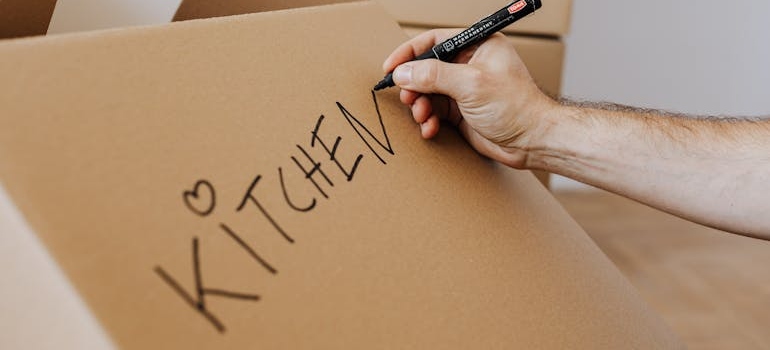 a woman labelling a box 'kitchen'